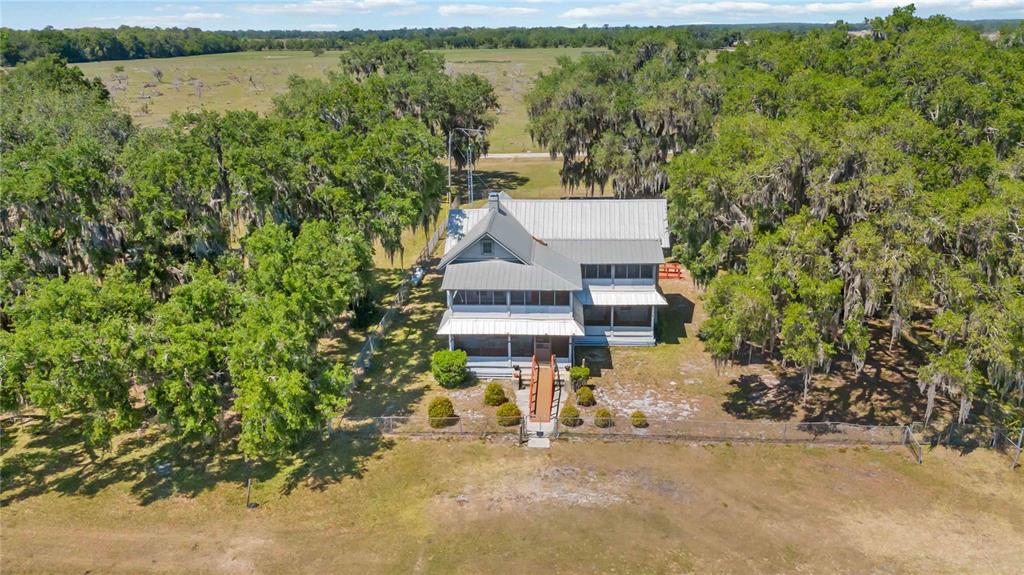 An aerial view of a two-story house with a metal roof surrounded by oak trees — 3650 LAKE TOHOPEKALIGA ROAD, ST CLOUD, FL