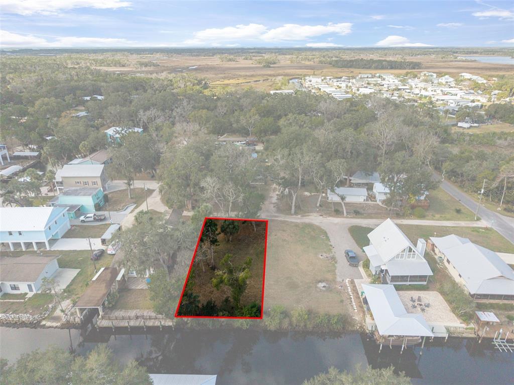 An aerial view shows a rectangular vacant lot outlined in red along a waterfront canal — 5799 S KINGDOM TERRACE, HOMOSASSA, FL