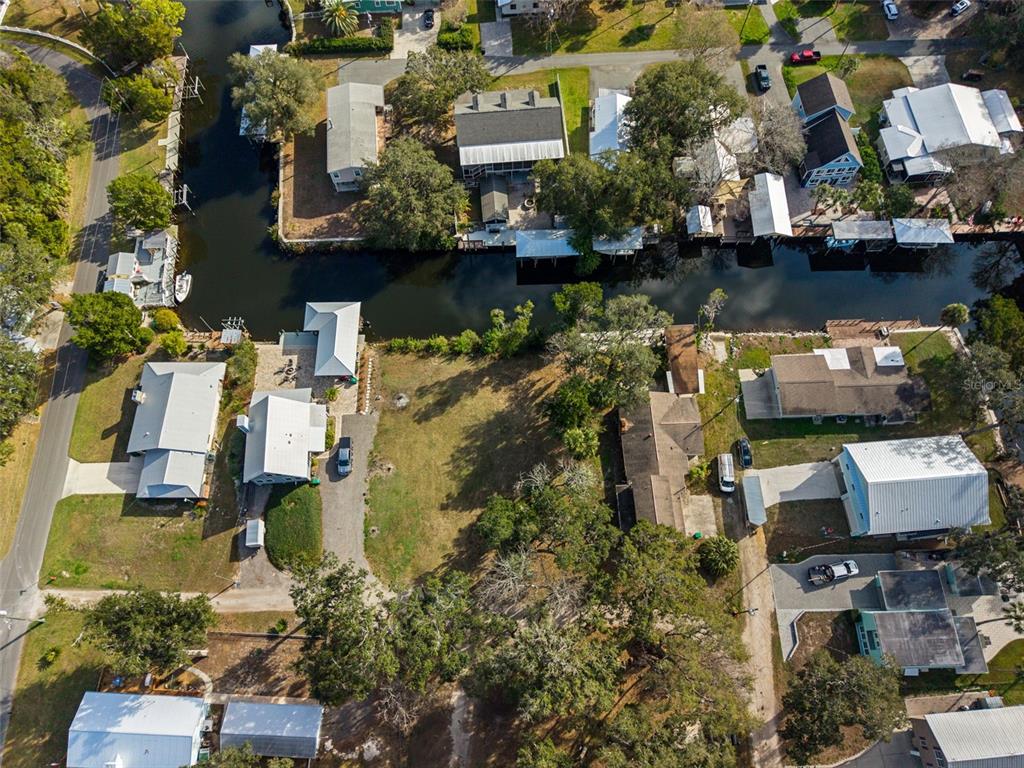 An aerial view shows several houses situated along a narrow canal with private boat docks — 5799 S KINGDOM TERRACE, HOMOSASSA, FL