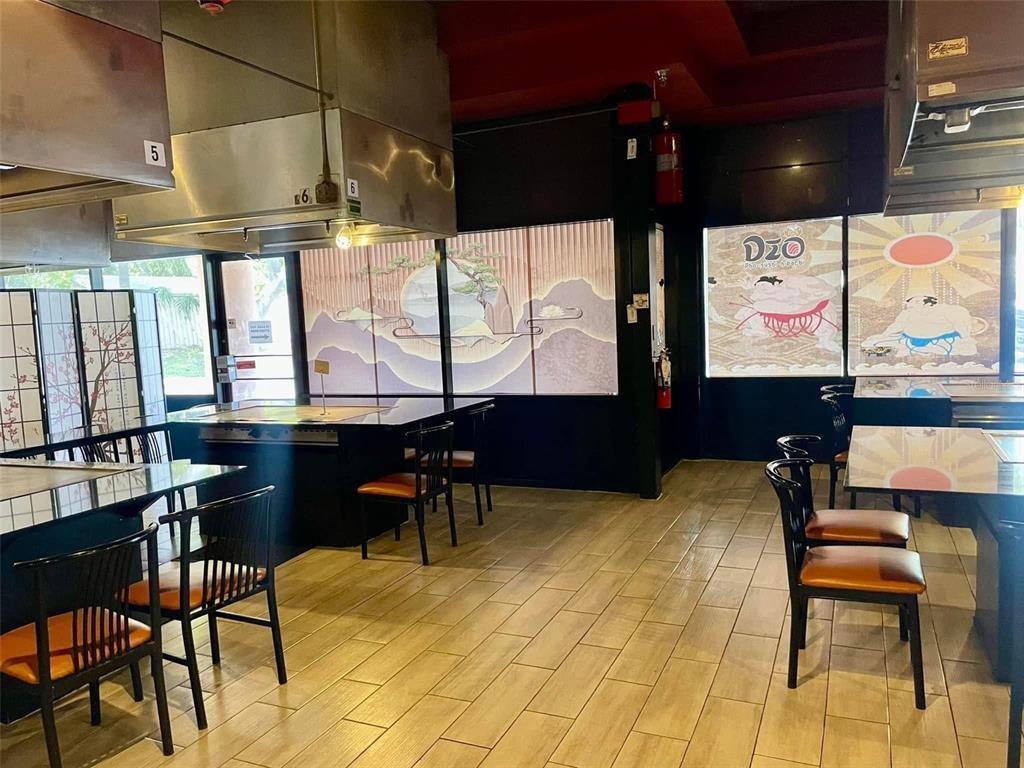 A restaurant interior features teppanyaki grills, wooden tables, chairs, and decorative window panels — 4500 66TH STREET N, ST PETERSBURG, FL