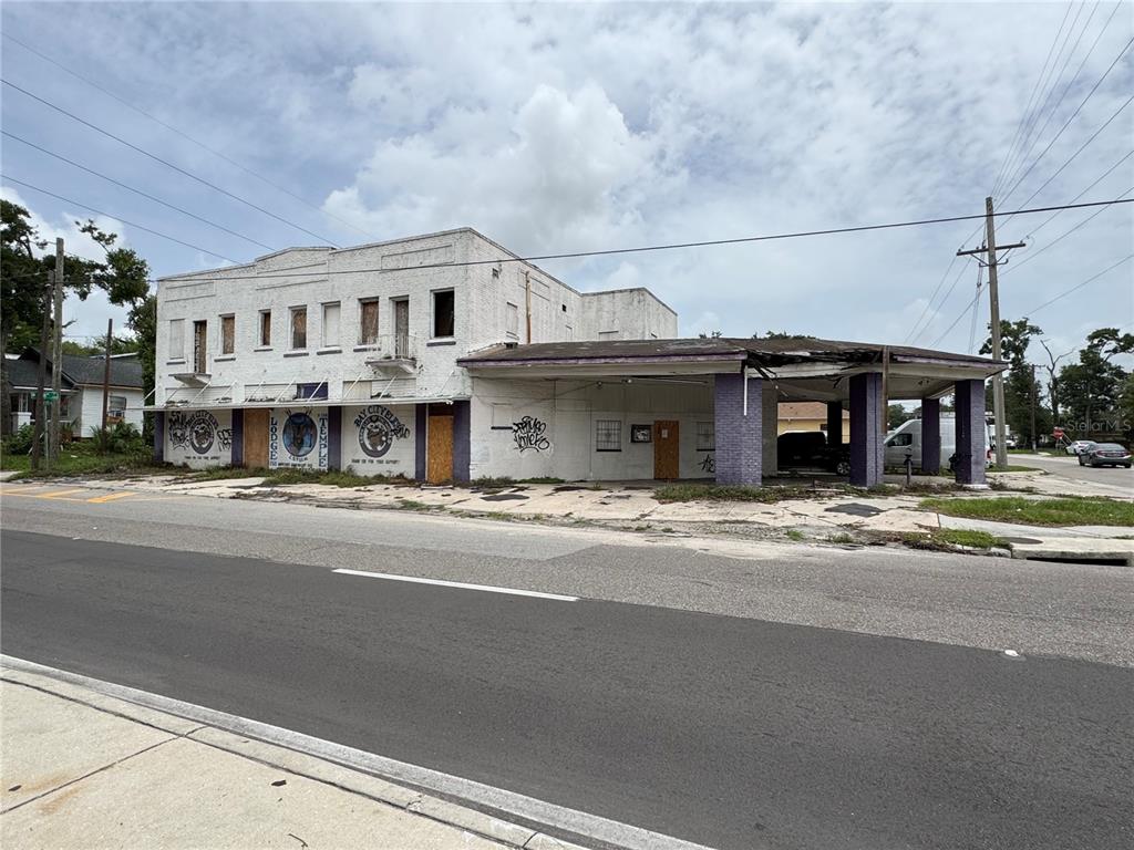 A weathered, two-story white building with a large attached canopy stands along a paved road — 2804 E COLUMBUS DRIVE, TAMPA, FL