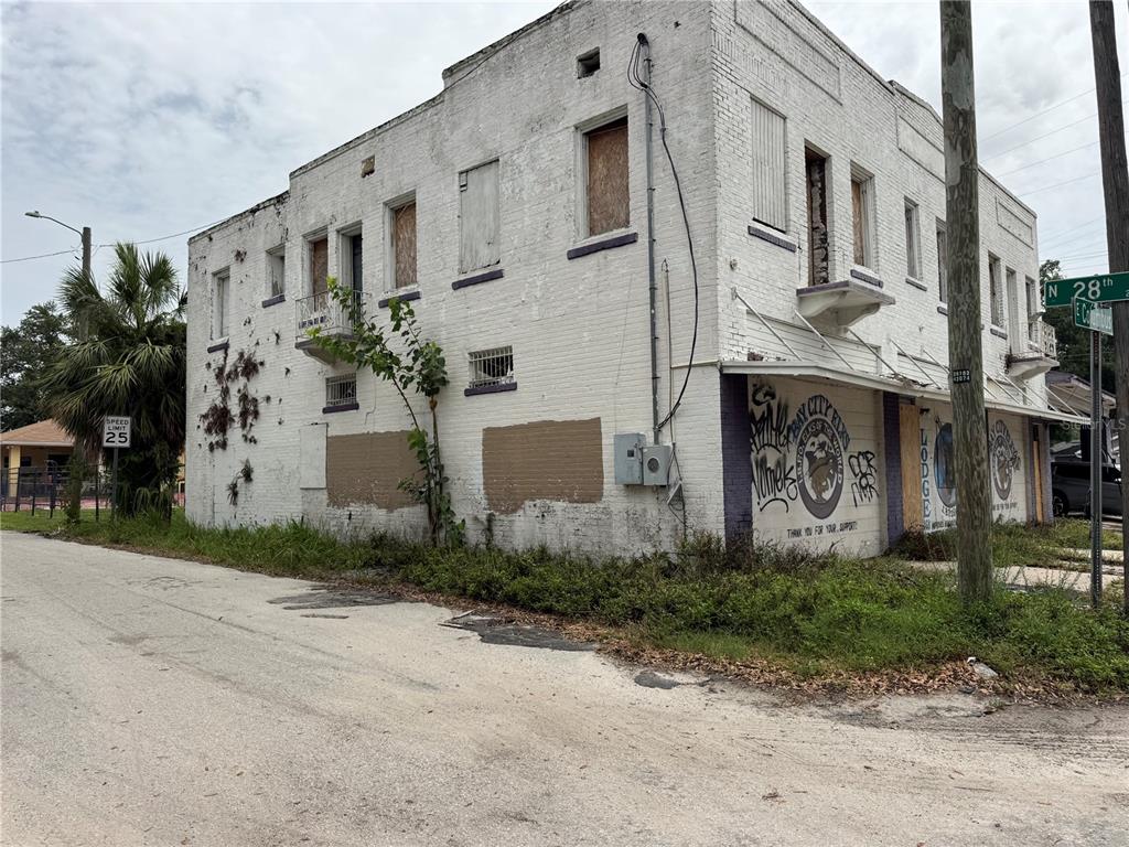 A weathered, two-story white brick building with boarded-up windows and graffiti on the exterior walls — 2804 E COLUMBUS DRIVE, TAMPA, FL