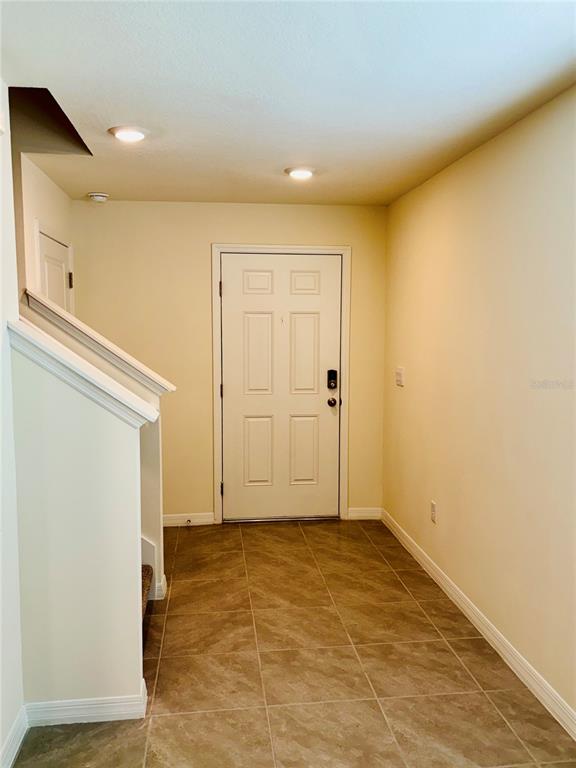 An entryway features a white front door, tiled flooring, and a staircase with a railing — 13649 WHISKEY DAISY DRIVE, DADE CITY, FL