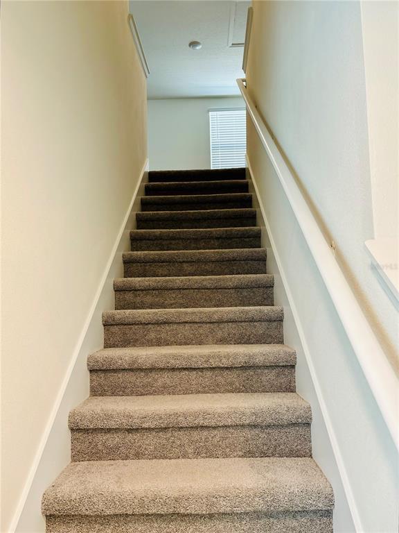 A straight staircase with brown carpet and white walls leads to an upper landing — 13649 WHISKEY DAISY DRIVE, DADE CITY, FL