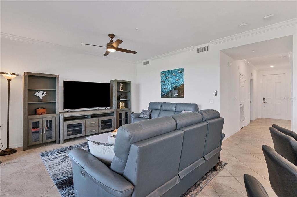 A living room features gray leather furniture, a media console with shelving, and tile flooring — 14071 HERITAGE LANDING BOULEVARD UNIT 326, PUNTA GORDA, FL