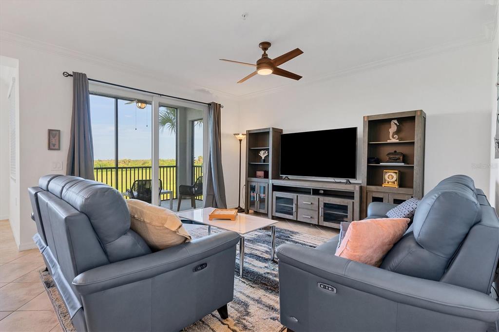 A living room features two blue leather sofas, a television console, and a balcony view — 14071 HERITAGE LANDING BOULEVARD UNIT 326, PUNTA GORDA, FL