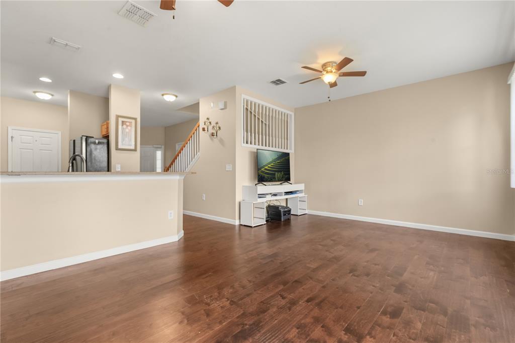 A living room with hardwood floors, a ceiling fan, and an open view to the kitchen — 10306 STONE MOSS AVENUE, TAMPA, FL