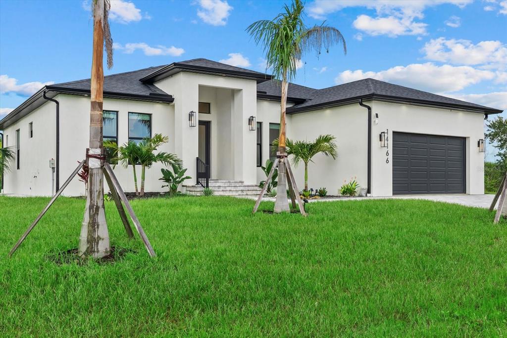 A modern, single-story white stucco house with a dark roof and a two-car garage — 14166 FORT WORTH CIRCLE, PORT CHARLOTTE, FL