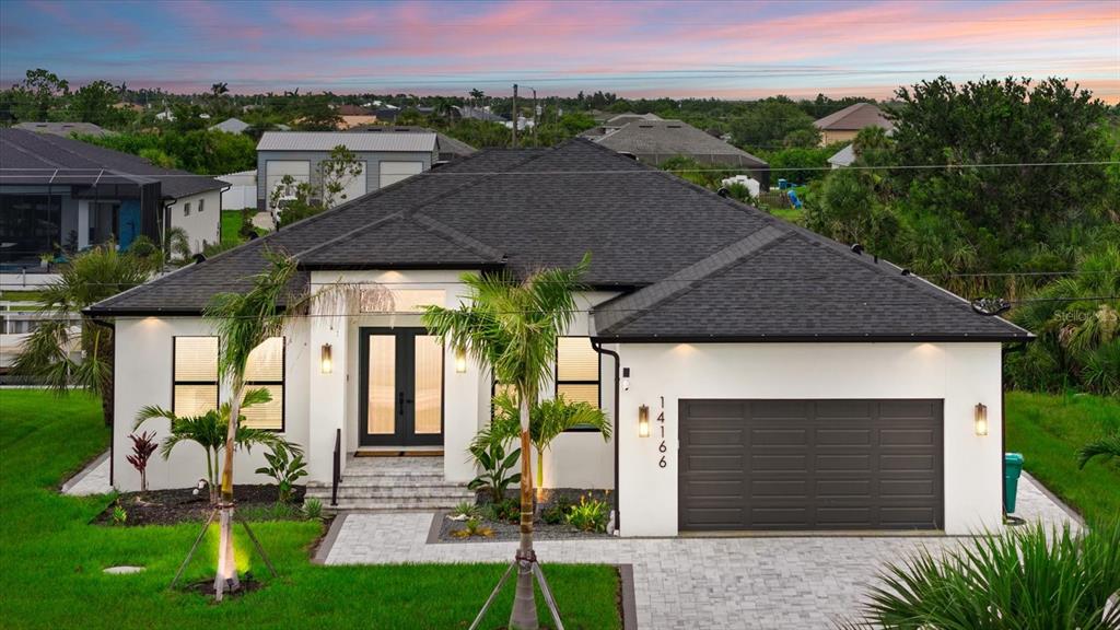 A modern single-story house with a white exterior, dark roof, and a two-car garage — 14166 FORT WORTH CIRCLE, PORT CHARLOTTE, FL