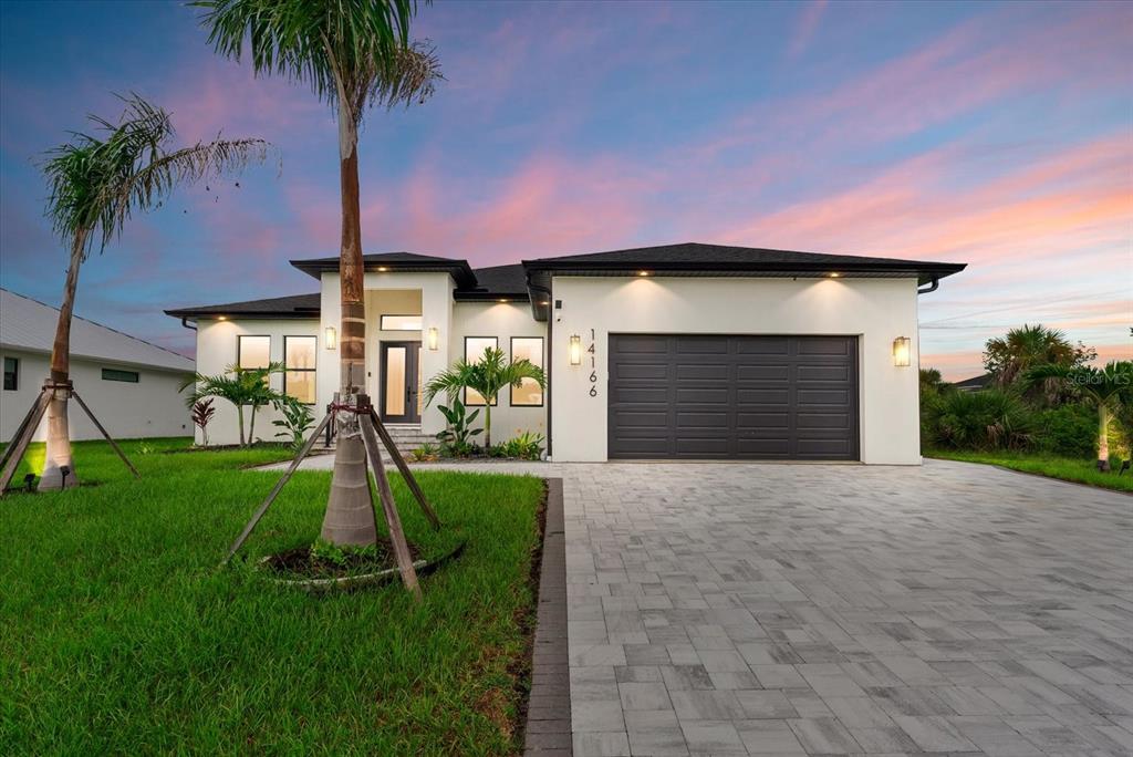A modern single-story house with a paved driveway, a two-car garage, and palm trees — 14166 FORT WORTH CIRCLE, PORT CHARLOTTE, FL