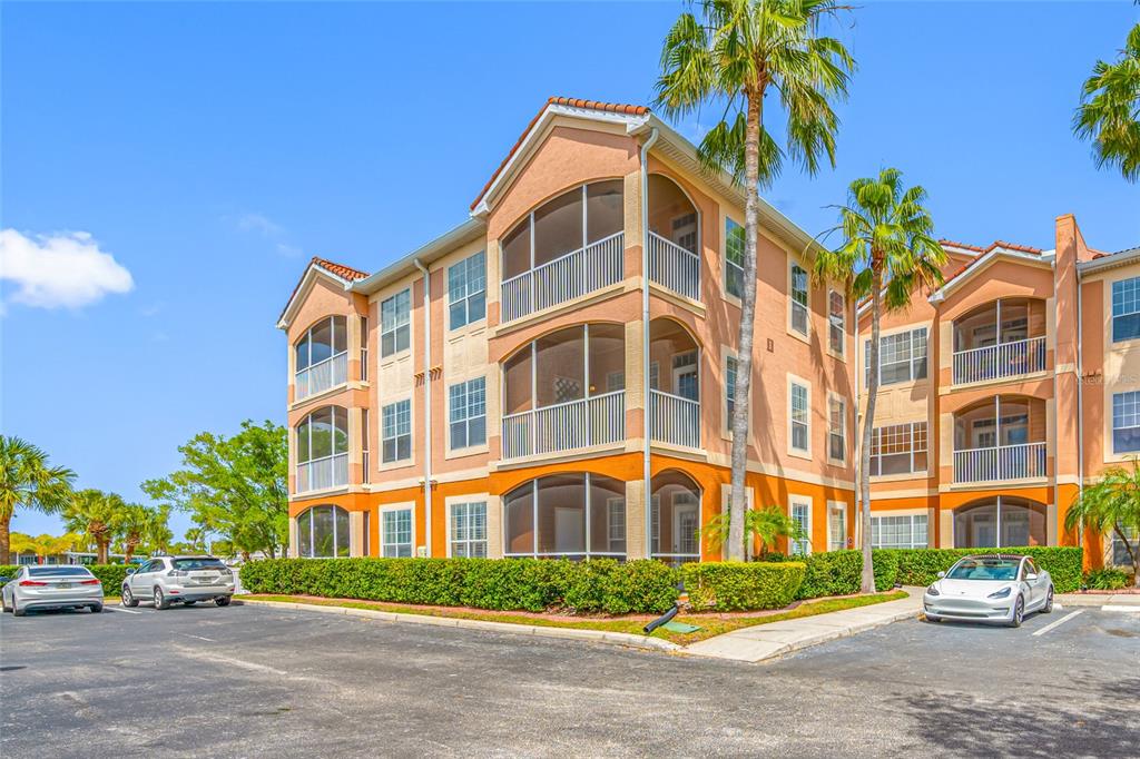 A three-story apartment building with screened balconies and a parking lot in front — 5000 CULBREATH KEY WAY UNIT 1-201, TAMPA, FL