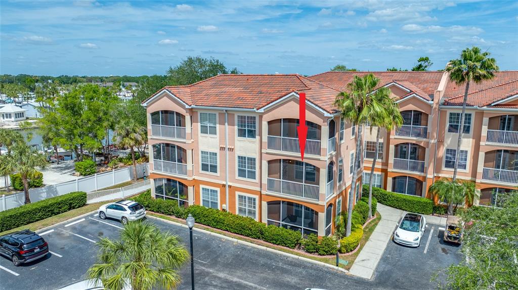An exterior view of a three-story apartment building with a red arrow pointing to a balcony — 5000 CULBREATH KEY WAY UNIT 1-201, TAMPA, FL