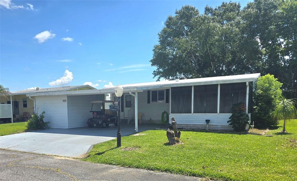 A single-story mobile home with a carport, a screened-in porch, and a golf cart — 379 TOWNBRIDGE DRIVE, HAINES CITY, FL