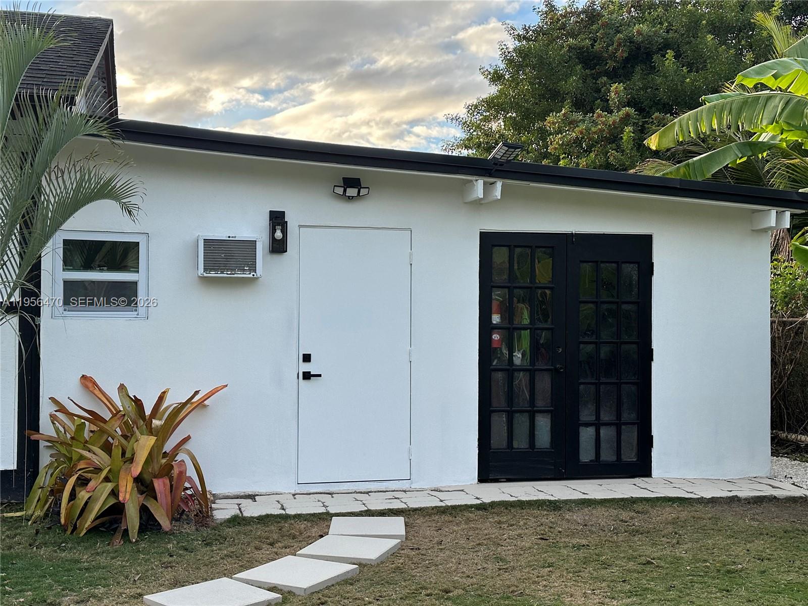 A white exterior wall features a window, a door, and a set of glass-paned doors — 18481 SW 208th St # 18481, Miami FL 33187, MIAMI, FL