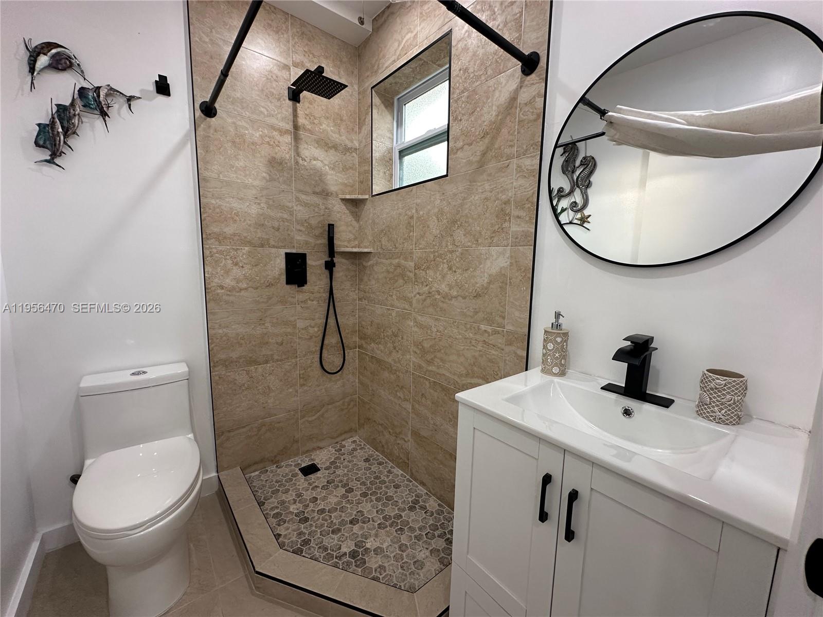 A bathroom features a tiled walk-in shower, a white vanity, and a round mirror — 18481 SW 208th St # 18481, Miami FL 33187, MIAMI, FL