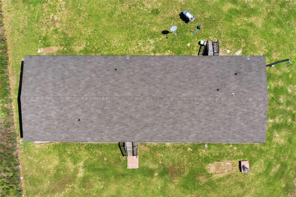 An aerial view shows a rectangular house with a shingled roof and two wooden decks — 9831 NE 100TH STREET, ARCHER, FL