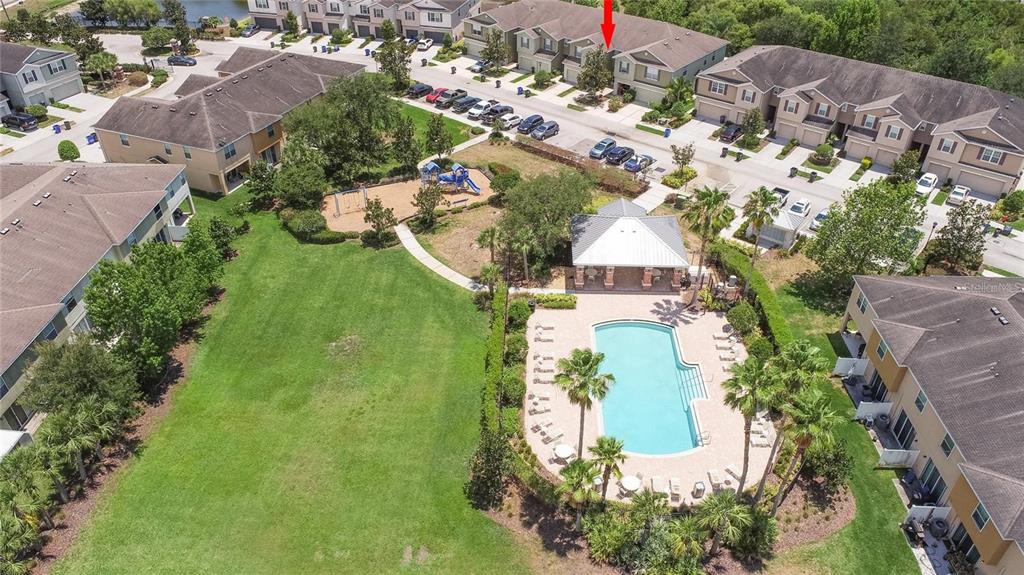An aerial view shows a townhouse community with a swimming pool, playground, and green space — 8931 TURNSTONE HAVEN PLACE, TAMPA, FL