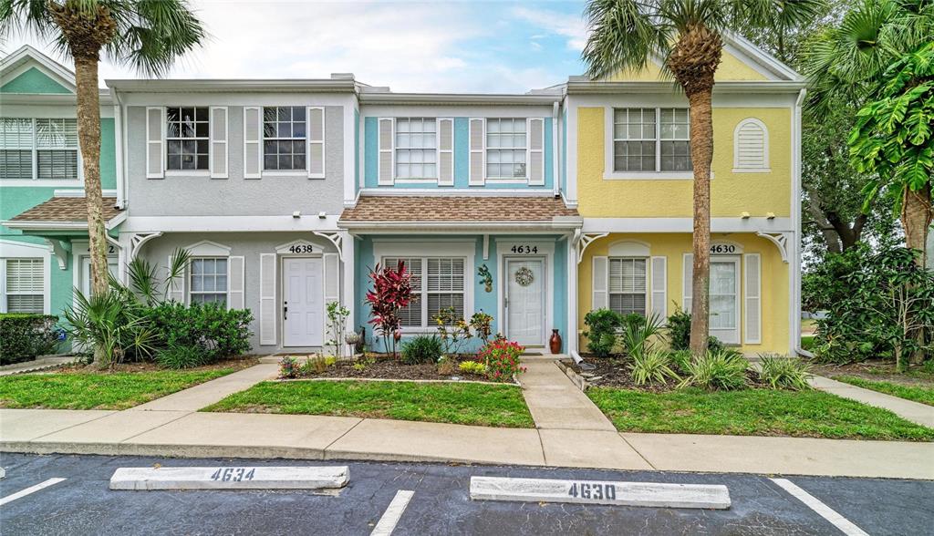 A row of three colorful townhouses with palm trees and assigned parking spaces in front — 4634 SABAL KEY DRIVE, BRADENTON, FL
