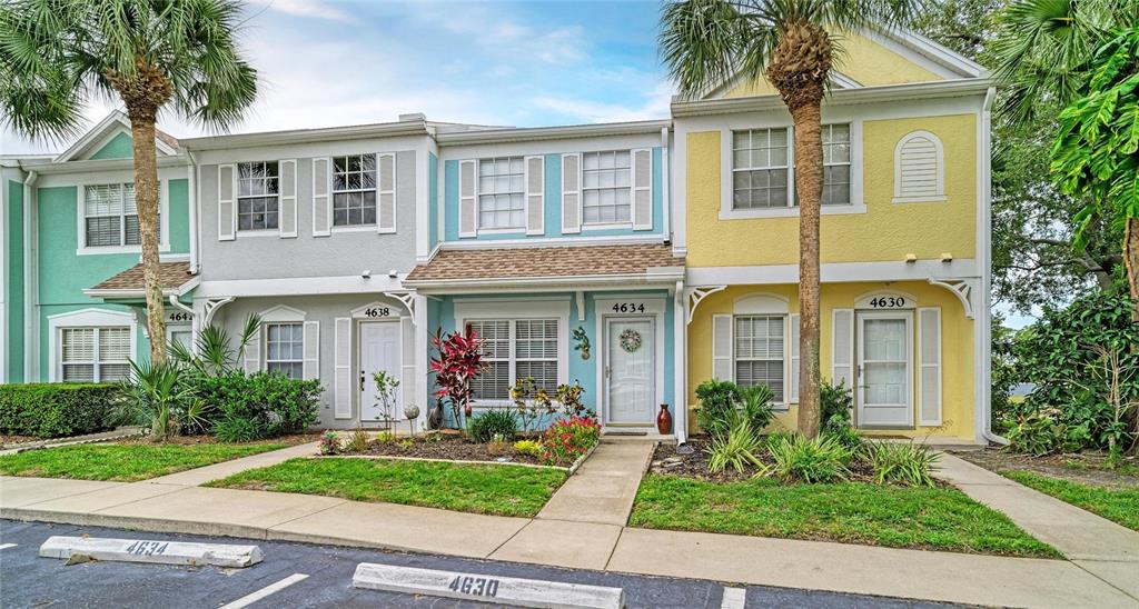 A row of multi-story townhomes with pastel-colored stucco siding and palm trees in the front — 4634 SABAL KEY DRIVE, BRADENTON, FL