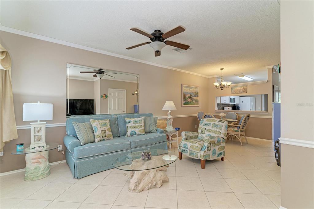 A living room features a blue sofa, an armchair, a glass coffee table, and tile flooring — 4634 SABAL KEY DRIVE, BRADENTON, FL