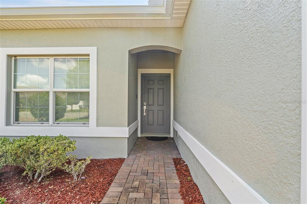 A gray front door is set in a recessed entryway with a brick walkway — 2825 ATTWATER LOOP, WINTER HAVEN, FL