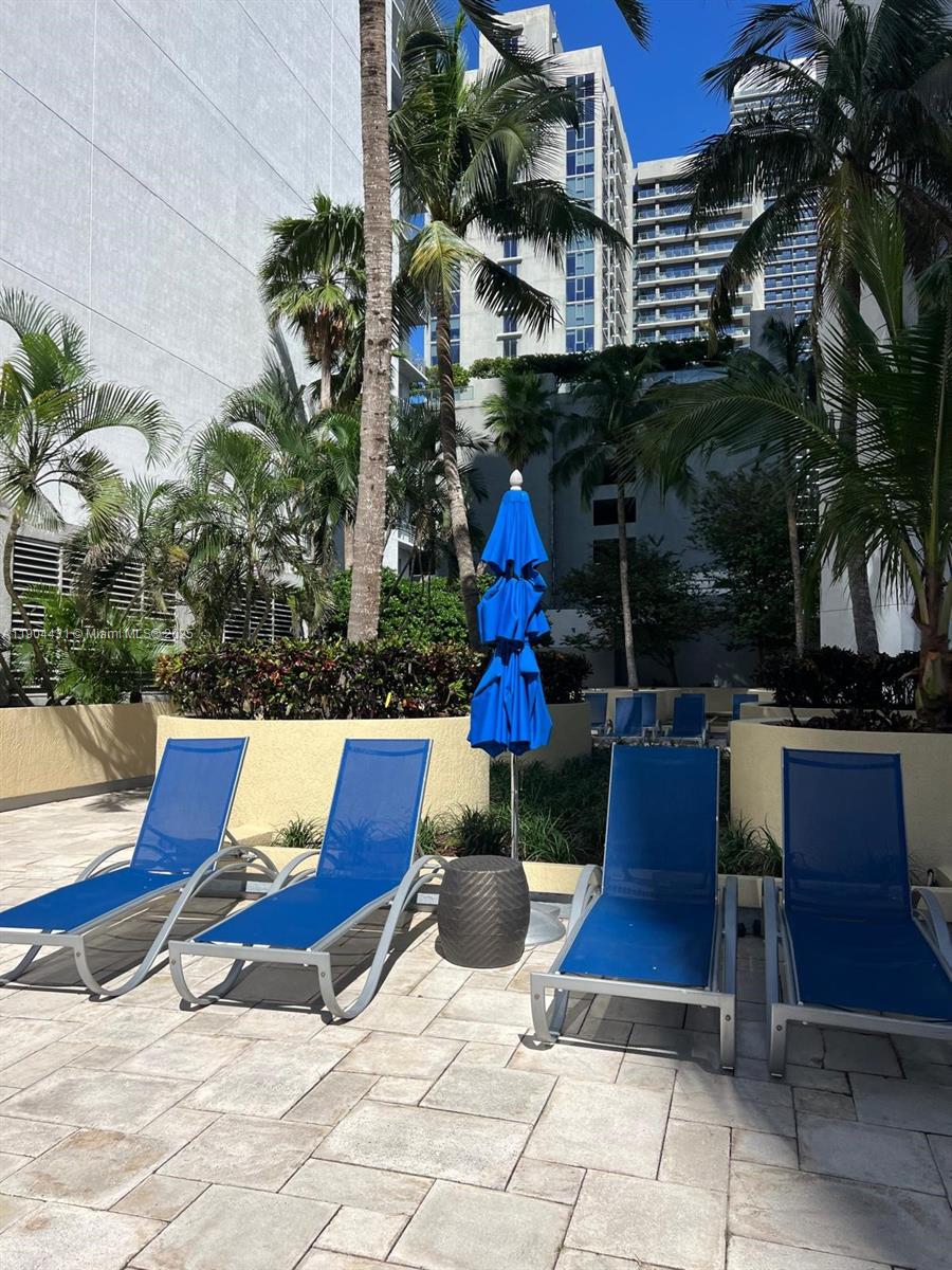 Four blue lounge chairs and a closed blue umbrella sit on a paved pool deck — 244 Biscayne Blvd # 303, Miami FL 33132, MIAMI, FL
