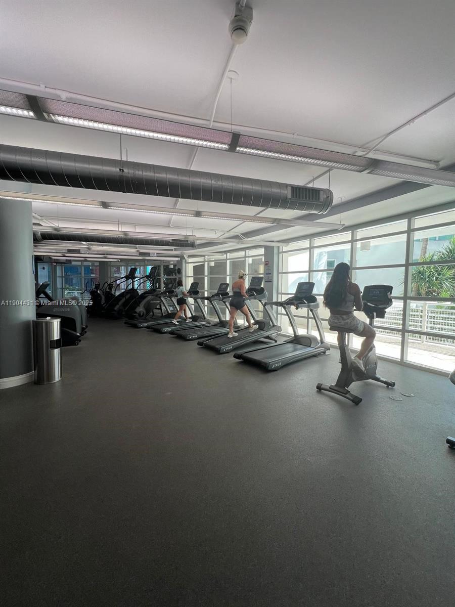 A gym features several treadmills and a stationary bike lined up near large windows — 244 Biscayne Blvd # 303, Miami FL 33132, MIAMI, FL
