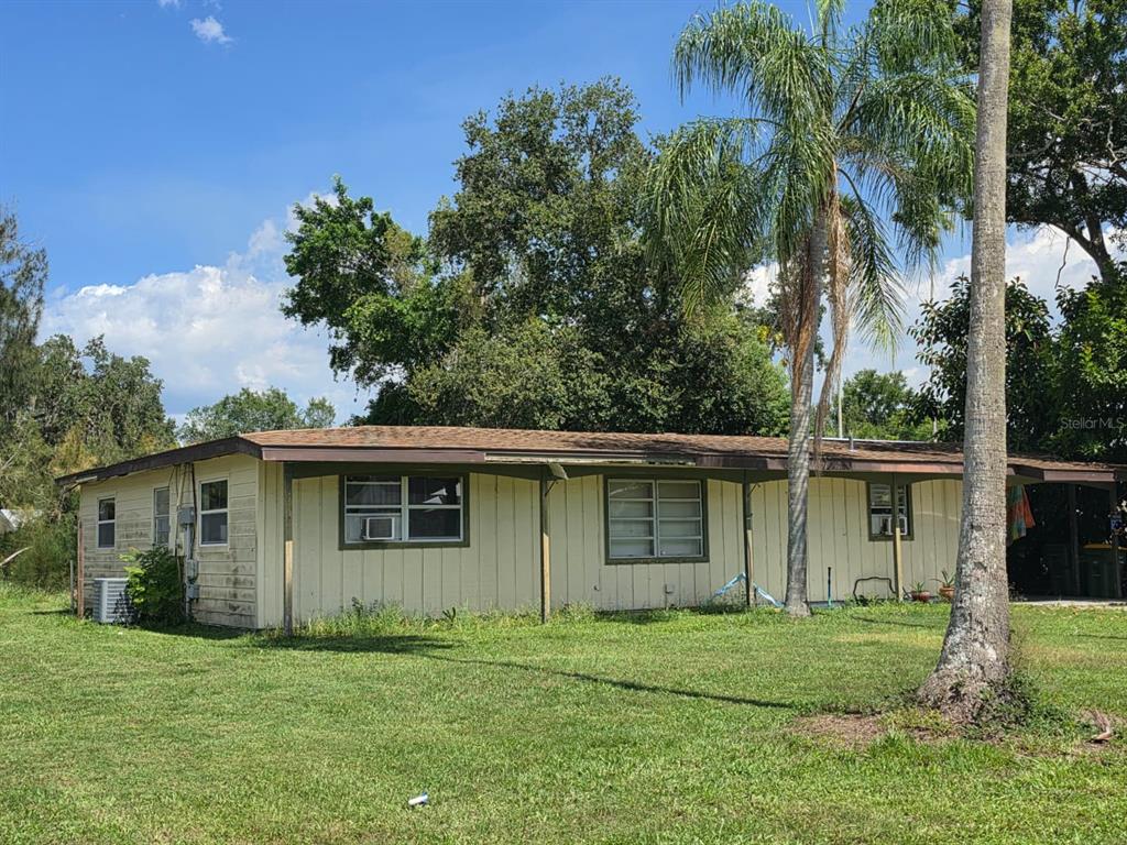 A single-story house with light-colored vertical siding and a brown roof sits on grass — 1125 PATTISON AVENUE, SARASOTA, FL