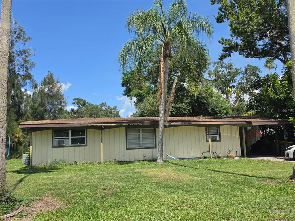 A single-story house with yellow vertical siding, a flat roof, and a palm tree out front — 1125 PATTISON AVENUE, SARASOTA, FL