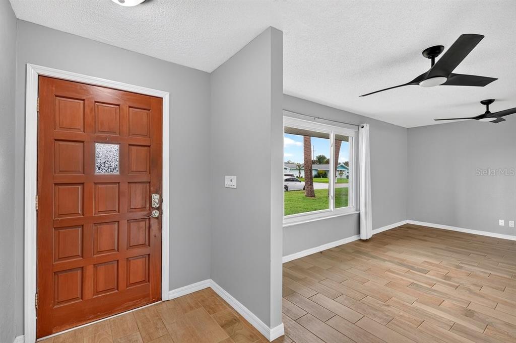 An entryway with a wooden door leads into a living room with gray walls — 1309 SUWANEE ROAD, DAYTONA BEACH, FL