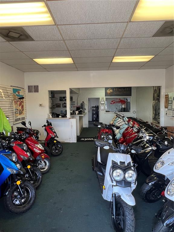 A showroom features several scooters parked on a green carpet under a drop ceiling — 853 US-41-BYP UNIT 853, VENICE, FL