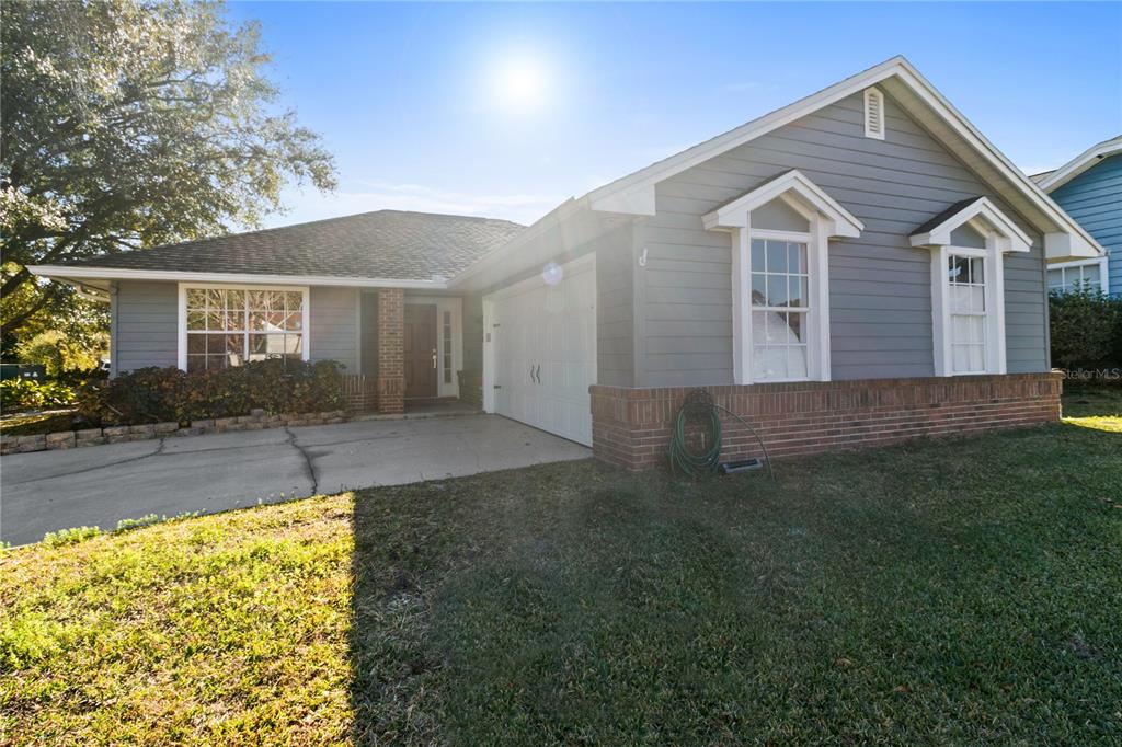 A single-story house with gray siding, a brick base, and a two-car garage — 6500 GROSVENOR LANE, ORLANDO, FL