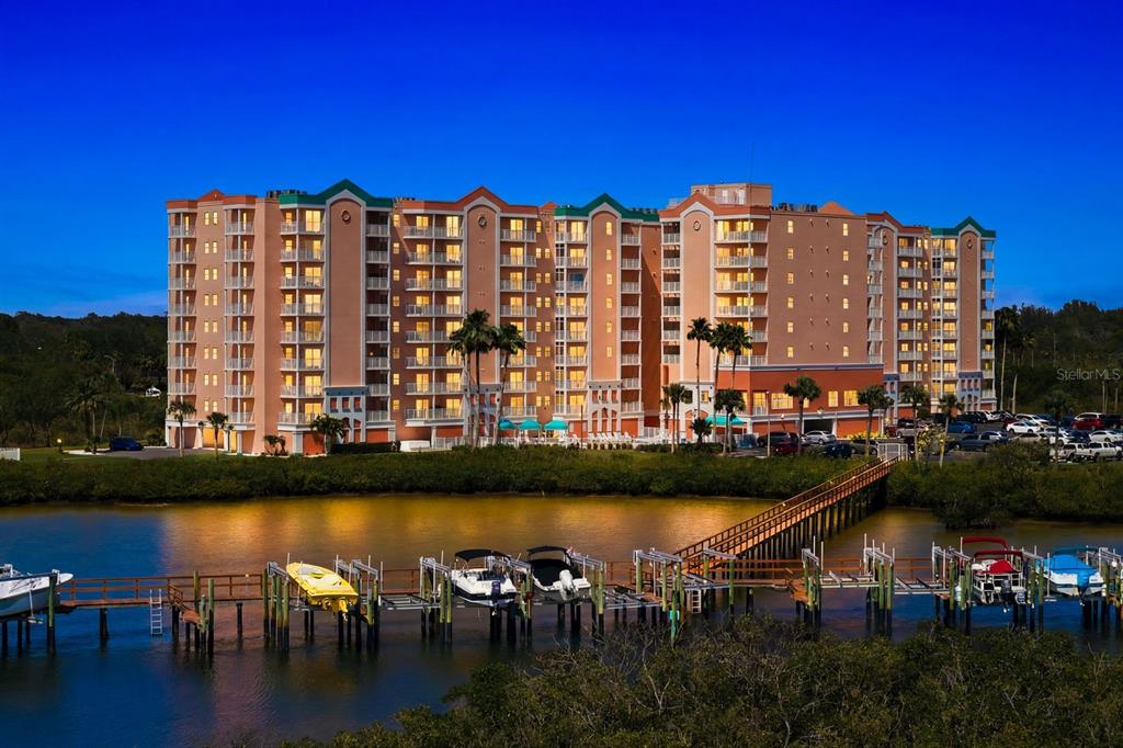A multi-story waterfront apartment building with a private boat dock at dusk — 4516 SEAGULL DRIVE UNIT 502, NEW PORT RICHEY, FL