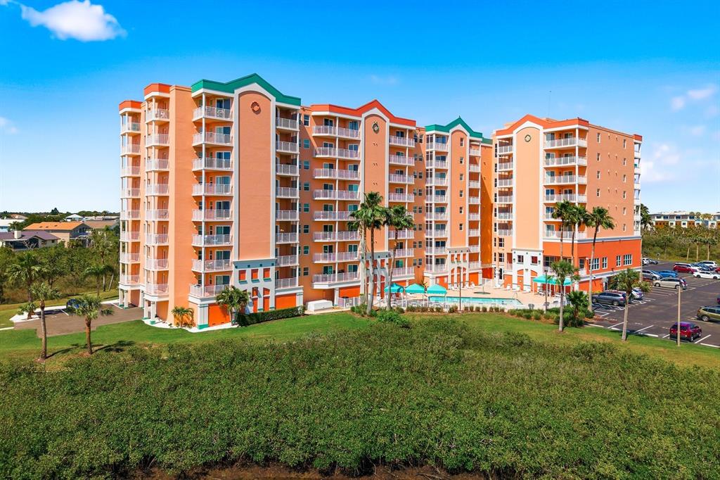 An exterior view of a multi-story orange apartment building with balconies and a swimming pool — 4516 SEAGULL DRIVE UNIT 502, NEW PORT RICHEY, FL
