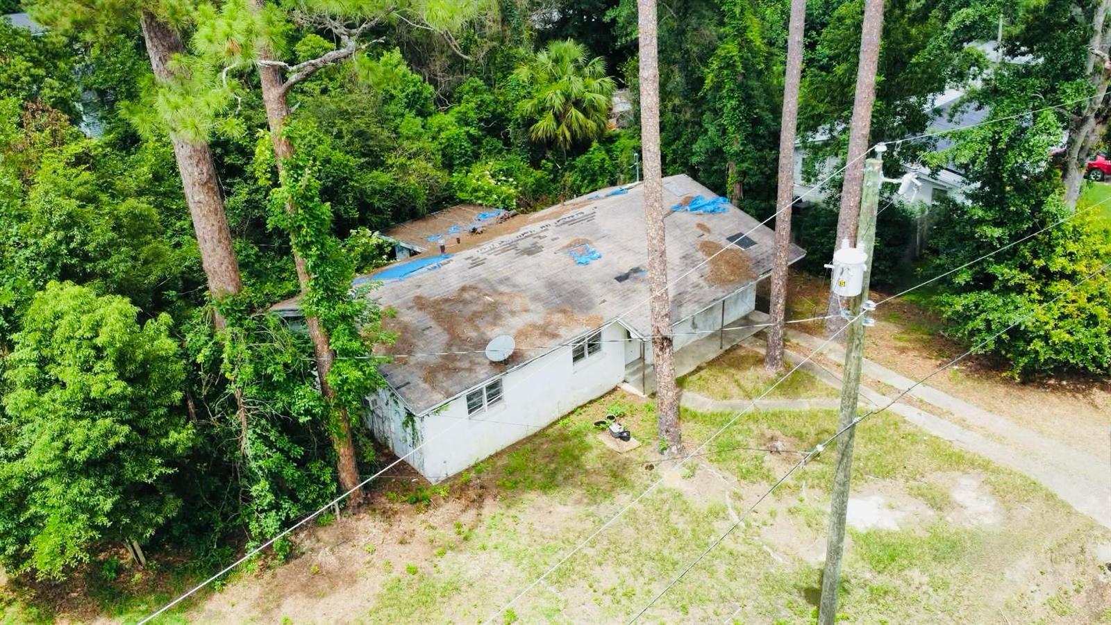An aerial view of a single-story house with a damaged roof covered by blue tarps — 20816 SE Ray Avenue, FL 32424, FL