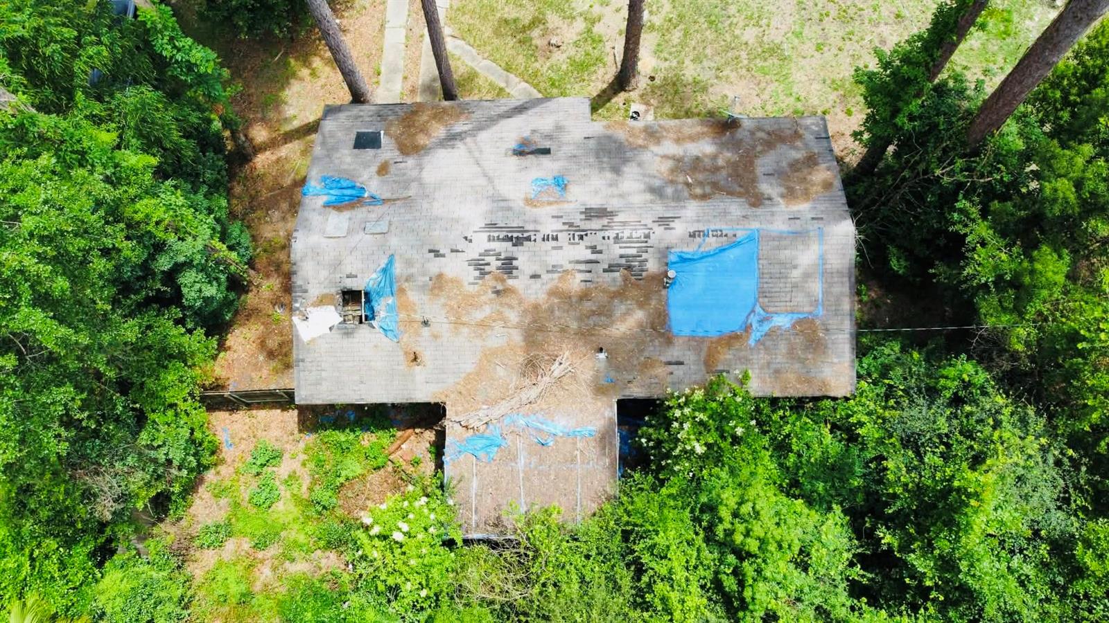 An aerial view shows a house with a damaged roof covered by several blue tarps — 20816 SE Ray Avenue, FL 32424, FL