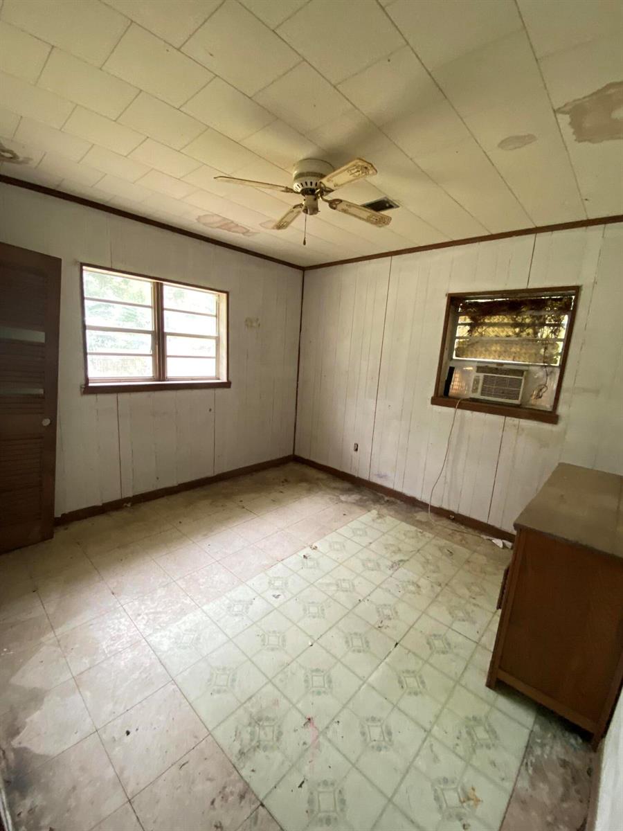 An empty bedroom features wood-paneled walls, a ceiling fan, a window air conditioner, and tile flooring — 20816 SE Ray Avenue, FL 32424, FL