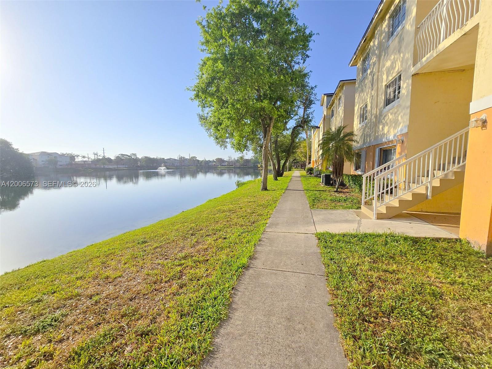 A sidewalk runs alongside a lake and a multi-story yellow apartment building with stairs — 3690 N 56th Ave # 912, Hollywood FL 33021, HOLLYWOOD, FL