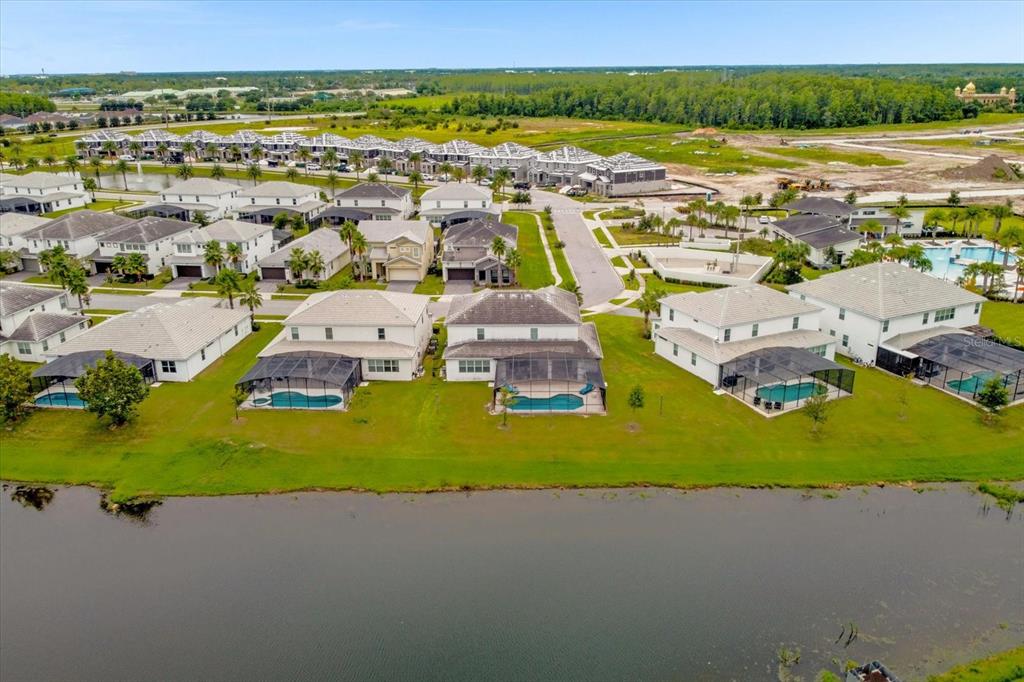 An aerial view shows a row of houses with screened-in pools overlooking a lake — 3951 OAKVILLE AVENUE, KISSIMMEE, FL