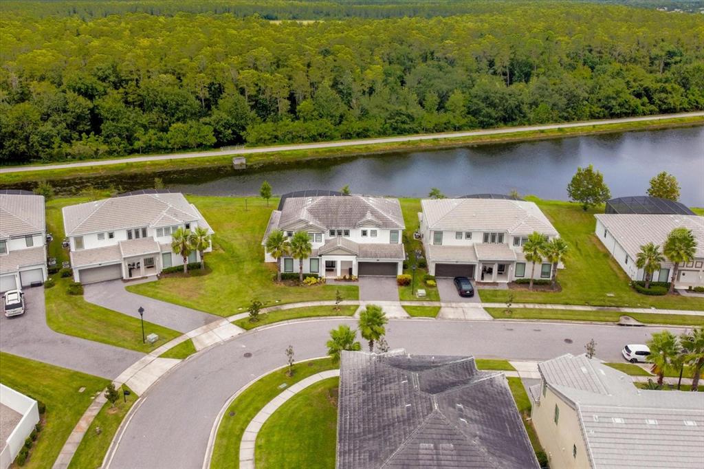 An aerial view shows several suburban houses with tiled roofs situated along a canal — 3951 OAKVILLE AVENUE, KISSIMMEE, FL