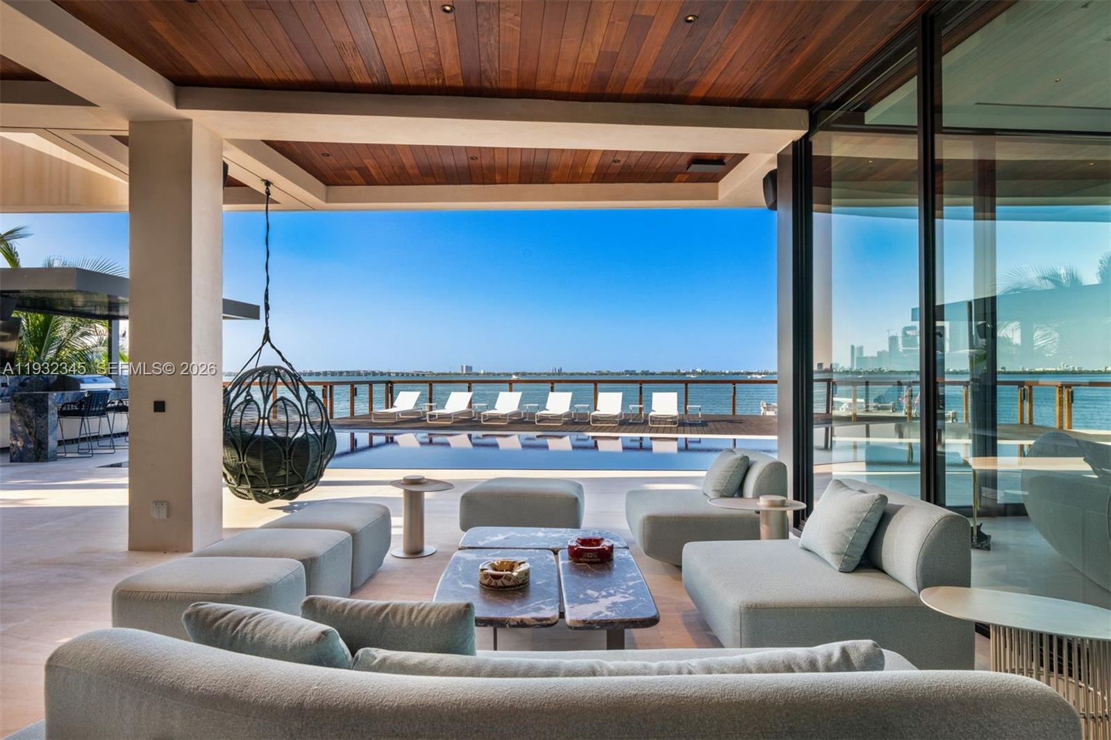 A modern outdoor living space features a pool, lounge seating, and a waterfront view — 1413 N Venetian Way, Miami FL 33139, MIAMI, FL