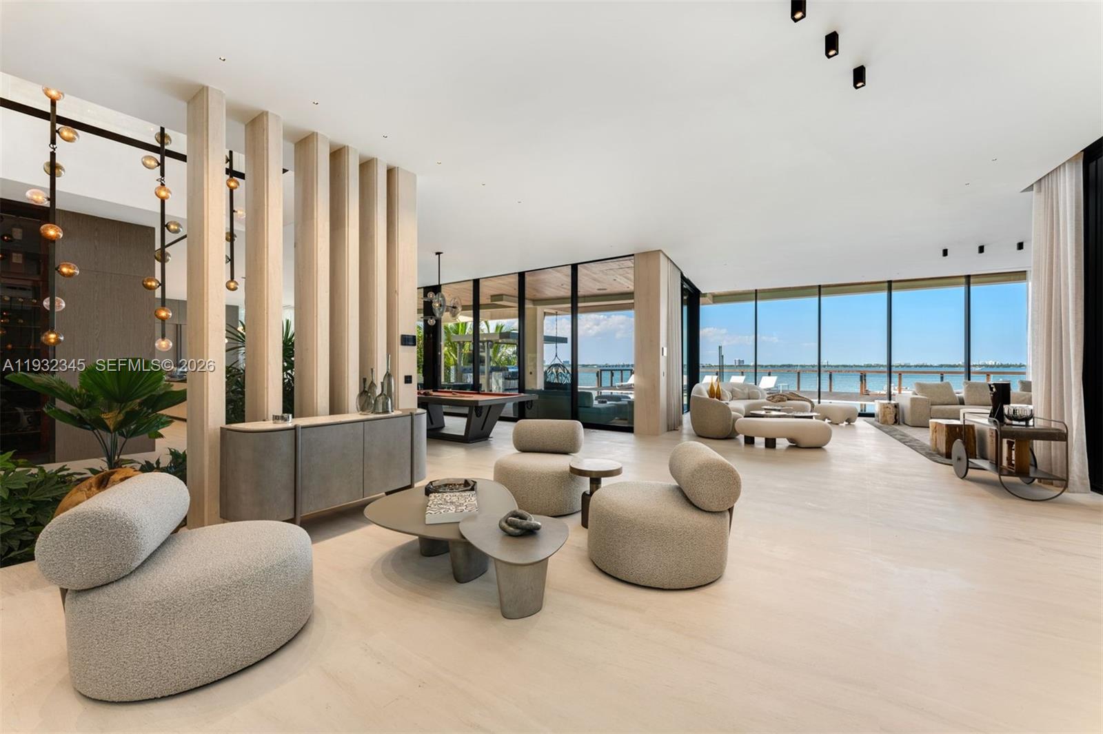 A spacious, modern living room features light wood slats, neutral furniture, and floor-to-ceiling windows — 1413 N Venetian Way, Miami FL 33139, MIAMI, FL