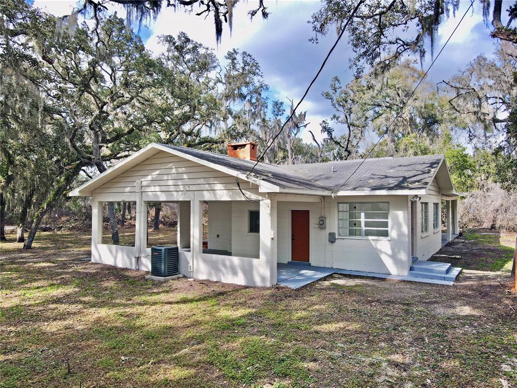 A single-story house with a screened porch, light siding, and a brick chimney — 34582 ORCHID PARKWAY, DADE CITY, FL
