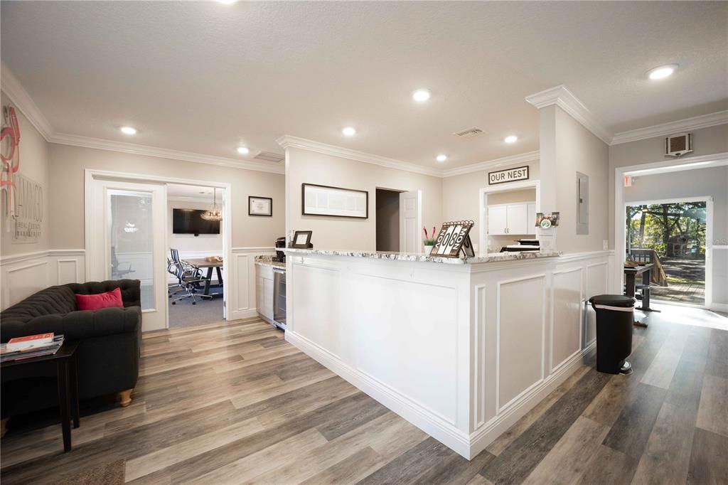 A reception area features a white desk, wood-look flooring, a dark sofa, and an office — 900 CLEVELAND AVENUE, WILDWOOD, FL