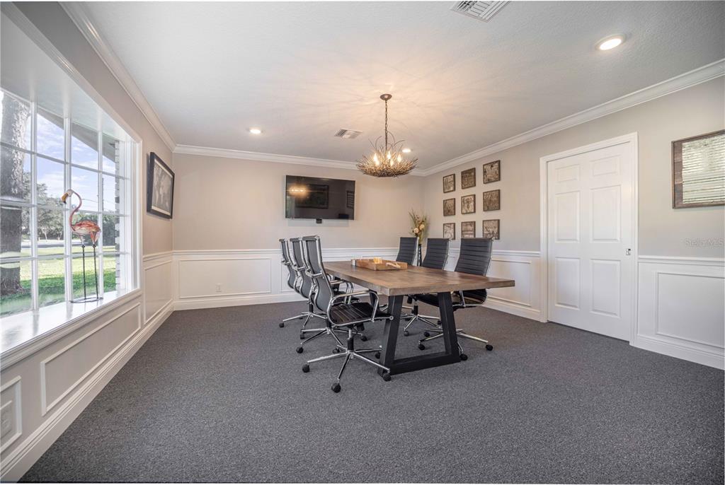 A dining room with a wooden table, six office chairs, gray carpet, and wainscoting — 900 CLEVELAND AVENUE, WILDWOOD, FL