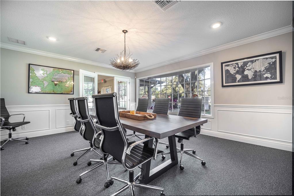 A conference room features a wooden table, black rolling chairs, and two framed world maps — 900 CLEVELAND AVENUE, WILDWOOD, FL