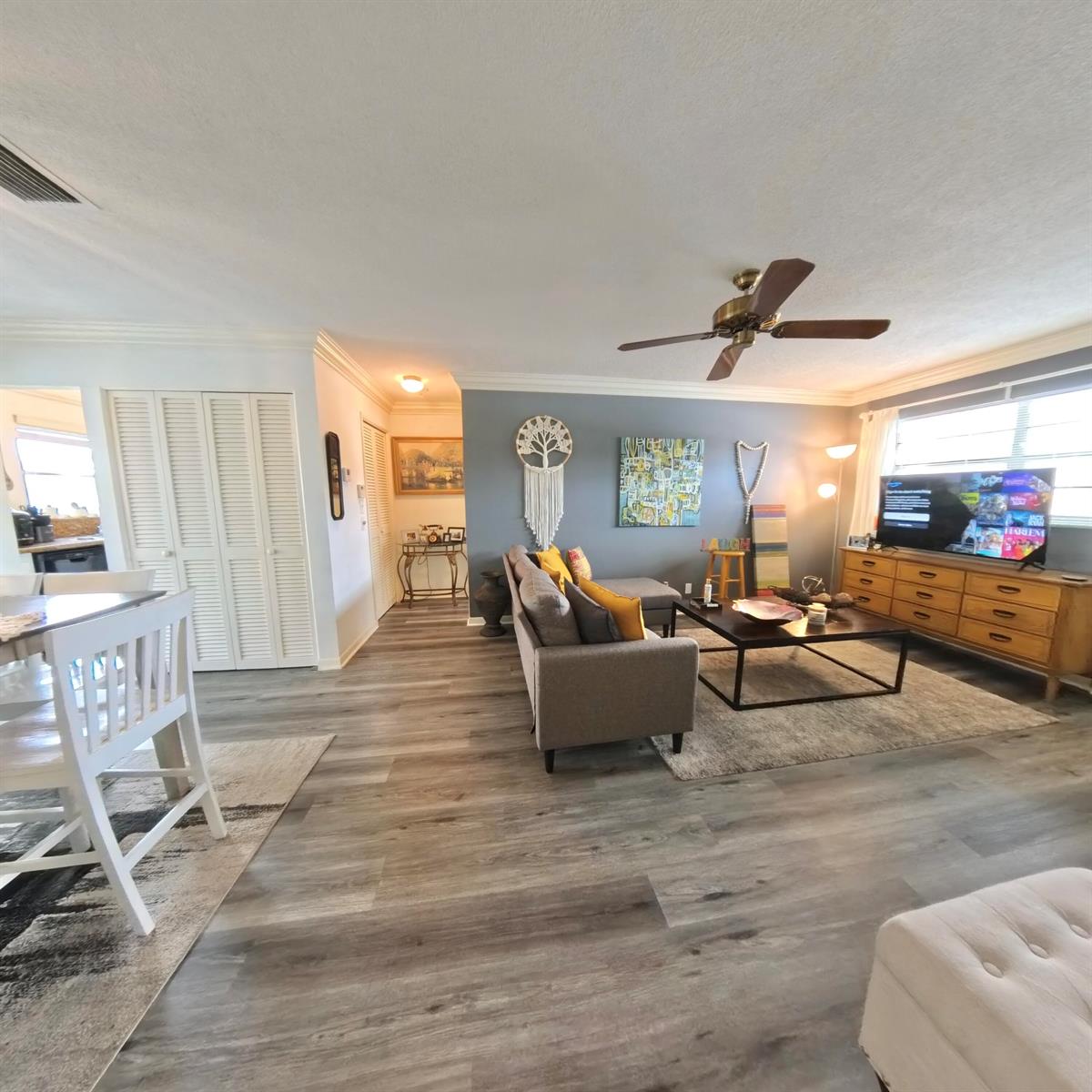 A living room features gray walls, wood-look flooring, a sectional sofa, and a media console — 4100 Crystal Lake Drive # 209, Pompano Beach FL 33064, POMPANO BEACH, FL