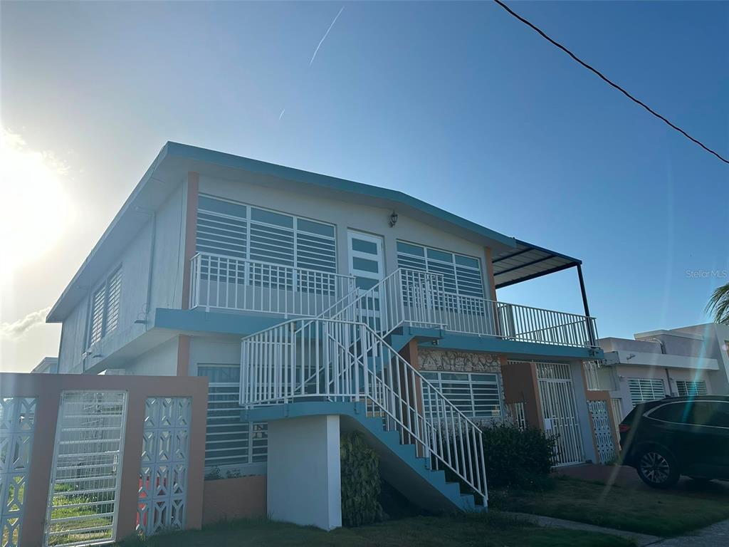 A two-story house with a white exterior, blue trim, and an external staircase — 7 JARDINES DE COUNTRY CLUB DEV. UNIT B-14, CAROLINA, PR