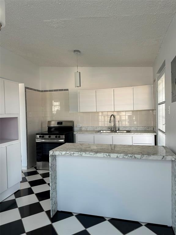 A kitchen features white cabinets, a marble-patterned island, and a black-and-white checkered floor — 7 JARDINES DE COUNTRY CLUB DEV. UNIT B-14, CAROLINA, PR