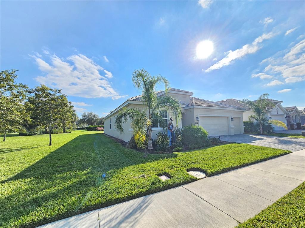 A single-story house with a beige exterior, a two-car garage, and a palm tree — 1351 OLYMPIC CLUB BOULEVARD, CHAMPIONS GATE, FL